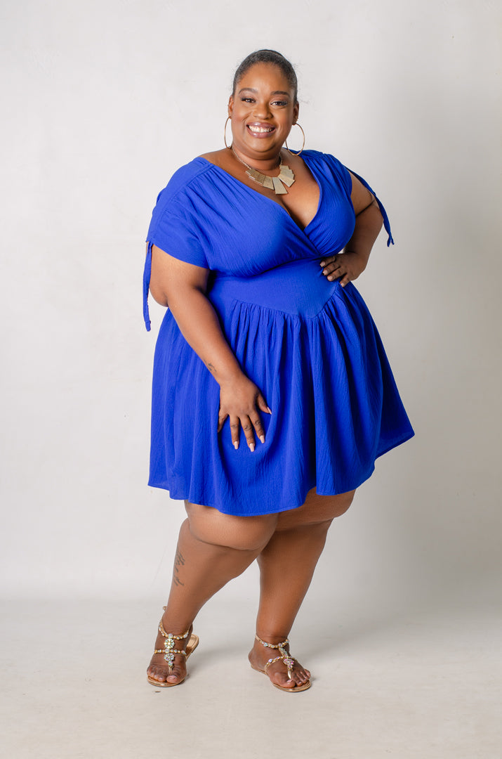 Plus size model wearing a blue dress against a plain background