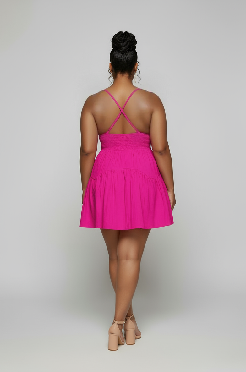 Person wearing a bright pink dress with thin straps on a plain background